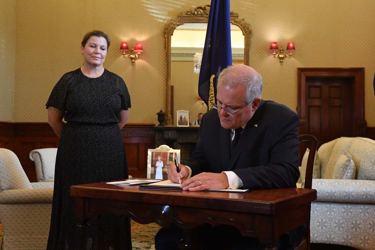 Prime Minister Scott Morrison signs a condolence book as wife Jenny looks on at Admiralty House following the death of Prince Philip, Duke of Edinburgh, in Sydney, Saturday, April 10, 2021. (AAP Image/Mick Tsikas) NO ARCHIVING