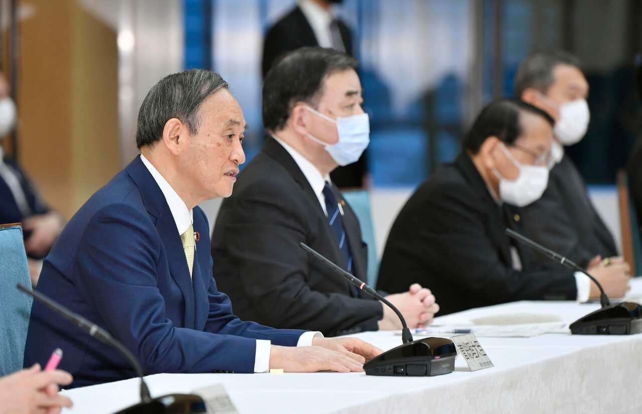 Japanese Prime Minister Yoshihide Suga (L) and members of his cabinet attend a meeting in Tokyo