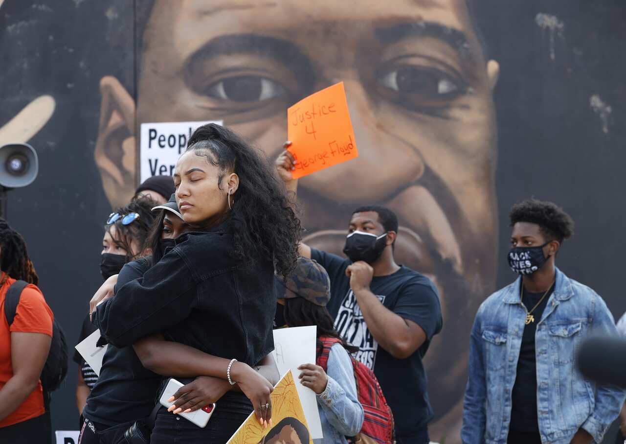 People react near a mural of George Floyd