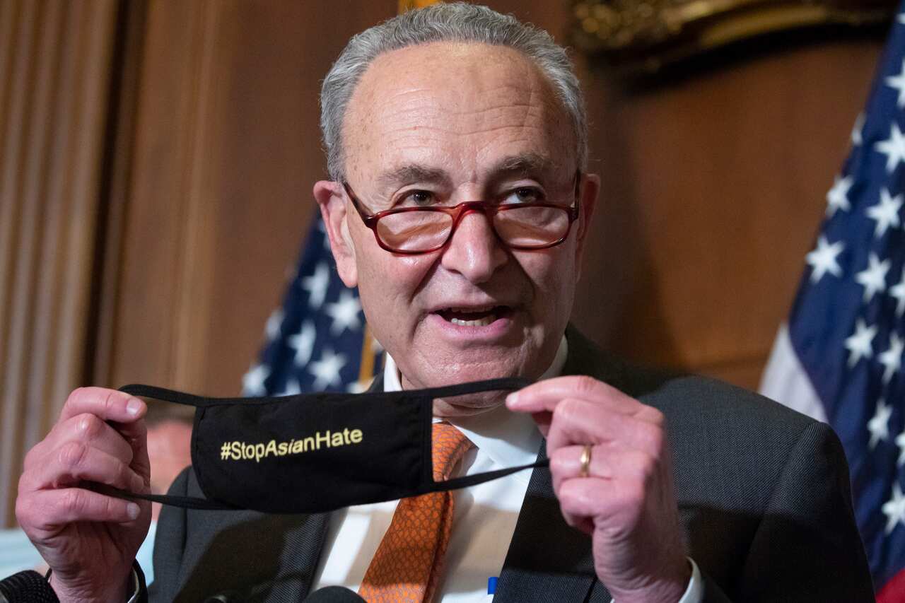 Senate Majority Leader Chuck Schumer holds up a face mask that reads 'Stop Asian Hate' after the Senate passed the COVID-19 Hate Crimes Act