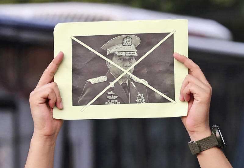 An activist holds up a defaced portrait of Myanmar's Commander-in-Chief Senior General Min Aung Hlaing during a rally against the military coup in Jakarta