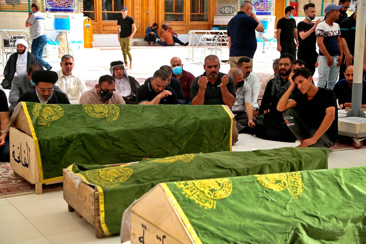 Mourners pray near the coffins of coronavirus patients killed in a hospital fire during their funeral at the Imam Ali shrine in Najaf, Iraq, on 25 April.