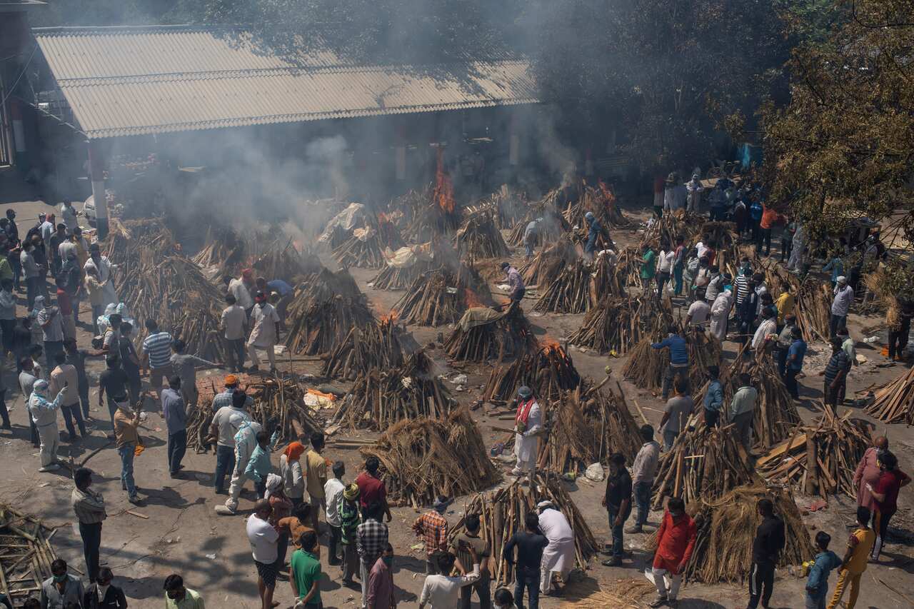 Multiple funeral pyres of those who died of COVID-19 burn at a ground that has been converted into a crematorium.