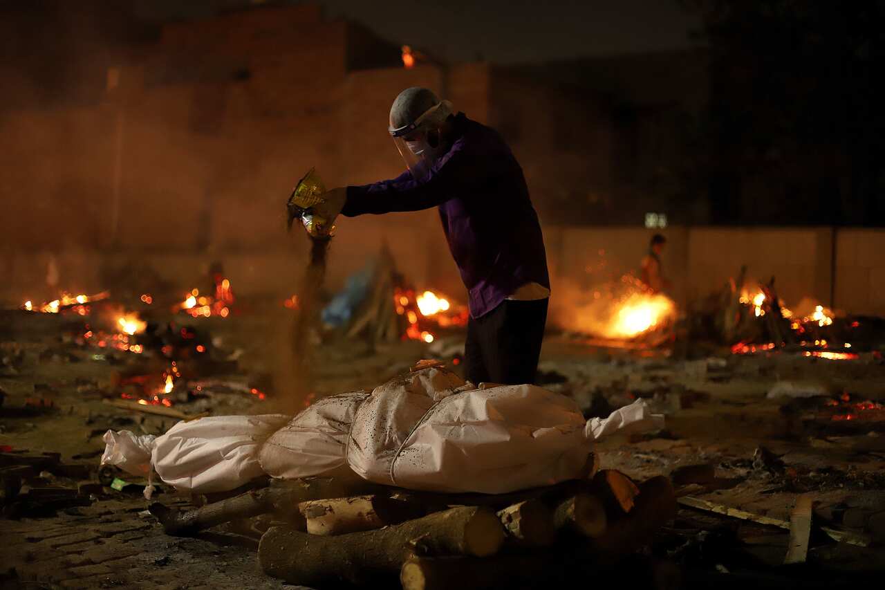 A man performs last funeral rites of a victim who died from COVID-19 at a cremation ground in New Delhi.