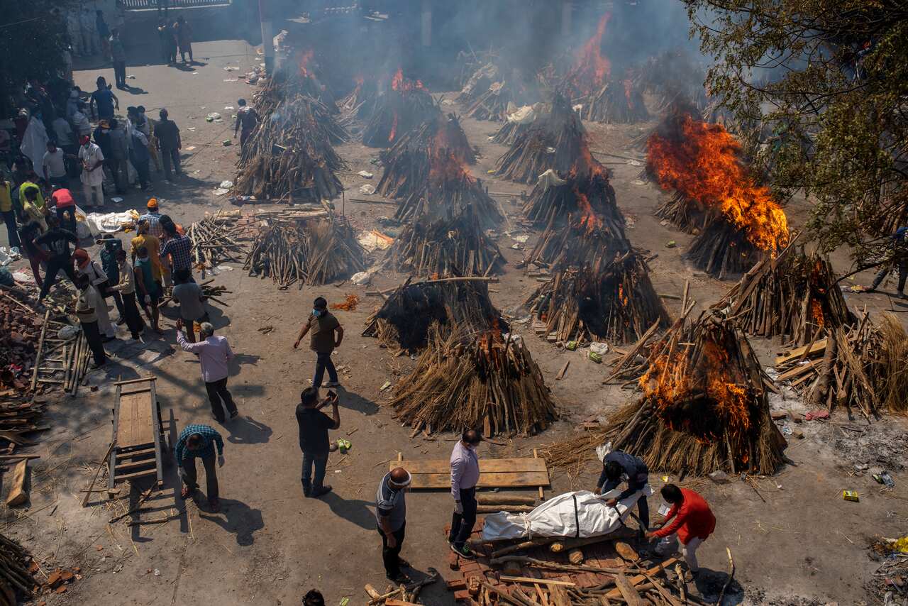 Multiple funeral pyres of COVID-19 victims burn at a ground that has been converted into a crematorium for mass cremation in New Delhi, on 24 April.
