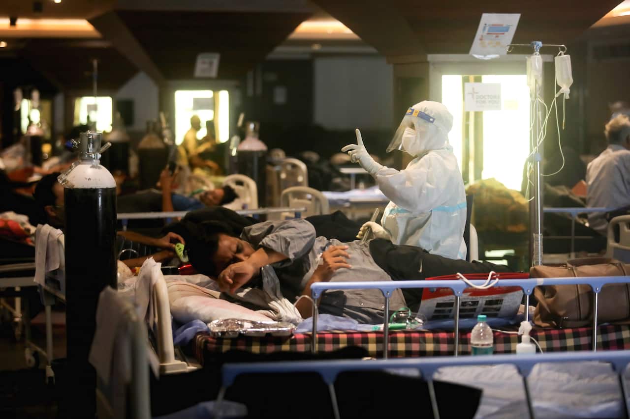 A health worker wearing a protective suit treating a patient inside a COVID-19 care center in India's New Delhi.