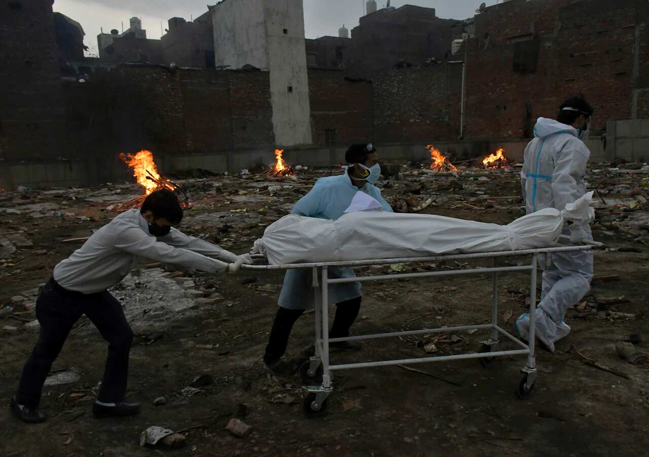 The body of a COVID-19 victim is wheeled in for cremation in a ground that has been converted into a crematorium in New Delhi, India, Thursday, May 6, 2021. 