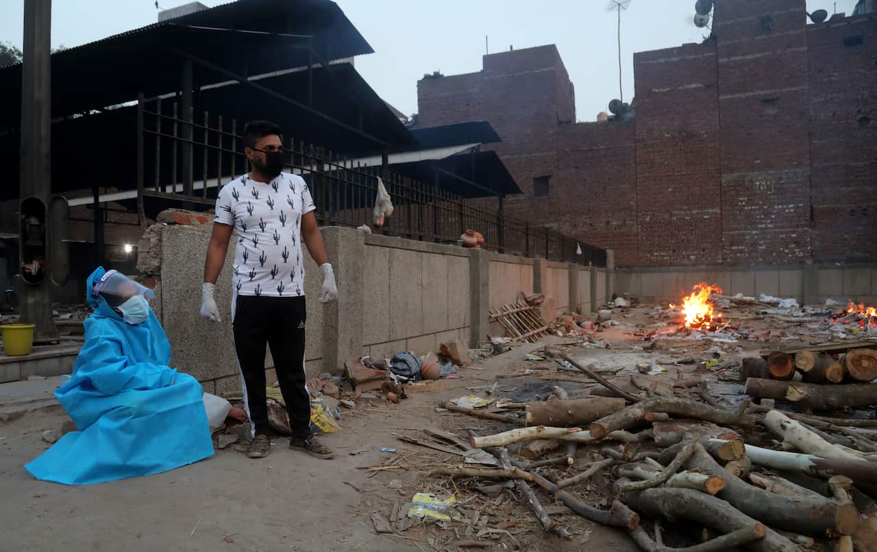 A woman wearing a protective suit mourns the death of her husband who has lost his life to COVID-19 at the Old Seemapuri crematorium in New Delhi.