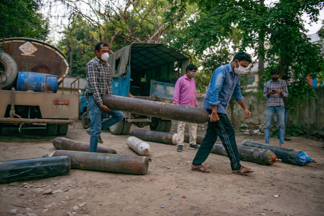 Family members of a COVID-19 patient carry an oxygen cylinder at Vasundhara.Ghaziabad Municipal Corporation, a district authority in Uttar Pradesh.