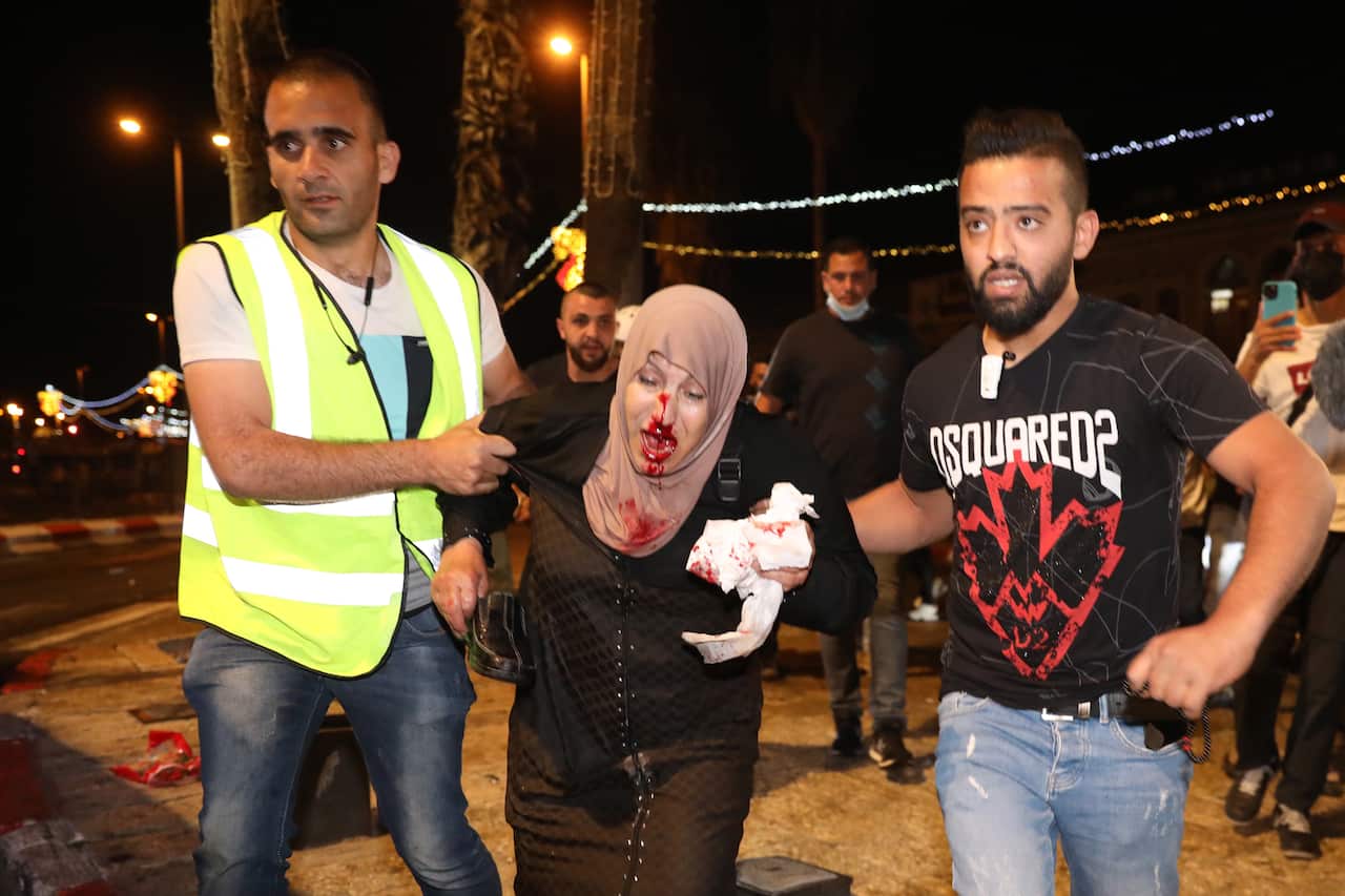 People help an injured Palestinian woman during a protest in Damascus Gate  in Jerusalem, 8 May 2021.
