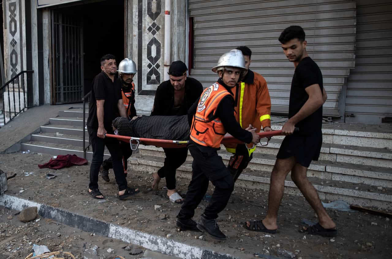 Palestinian rescuers evacuate an elderly woman from a building following Israeli airstrikes on Gaza City, Wednesday, May. 12, 2021