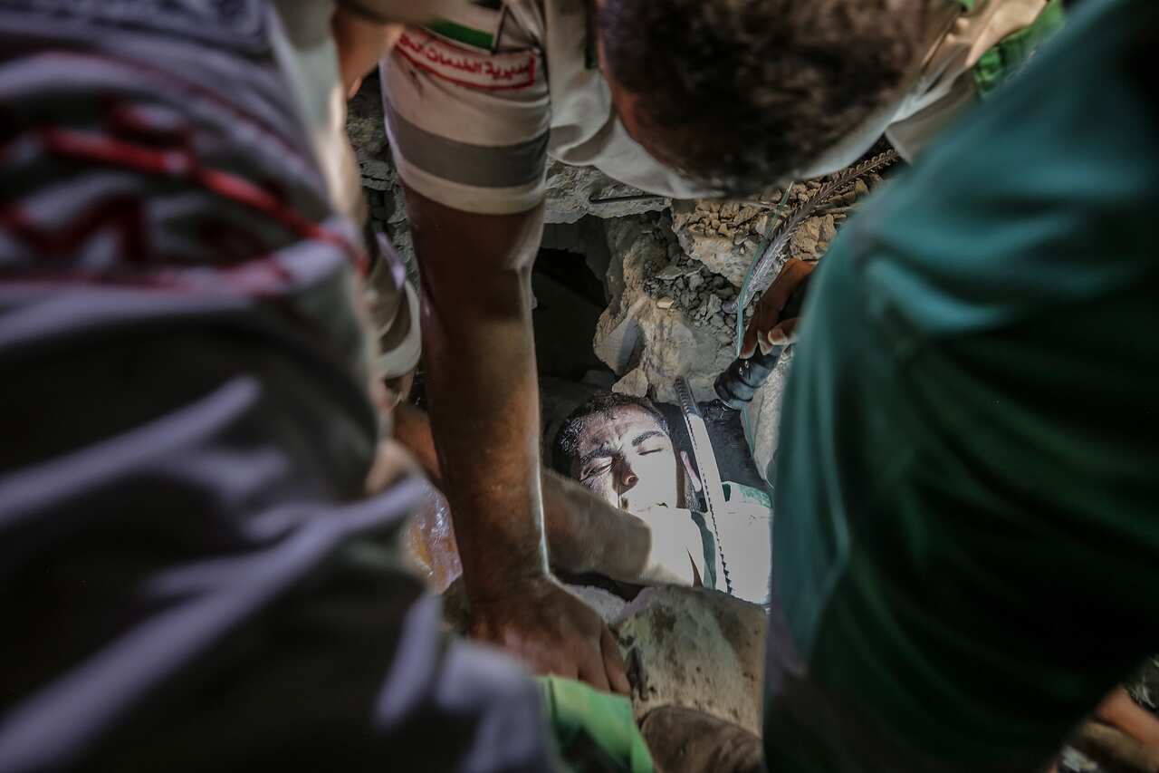 Palestinian Civil Defense men search for people between the rubble of a destroyed house in Gaza City, 16 May 2021.