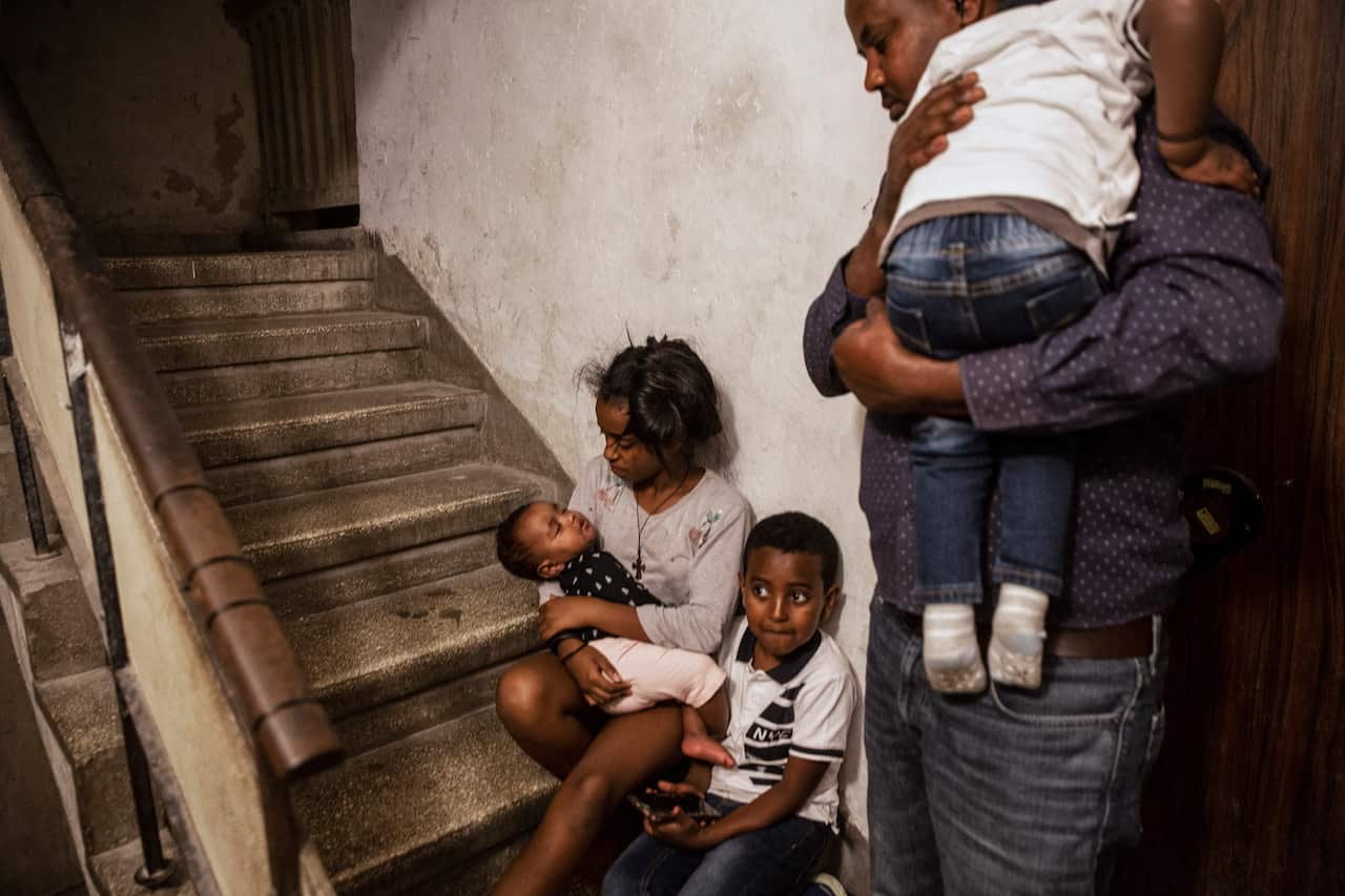 An Eritrean asylum seeker and his children take shelter outside their apartment in Ashdod, Israel, during a siren warning of rockets fired from Gaza.