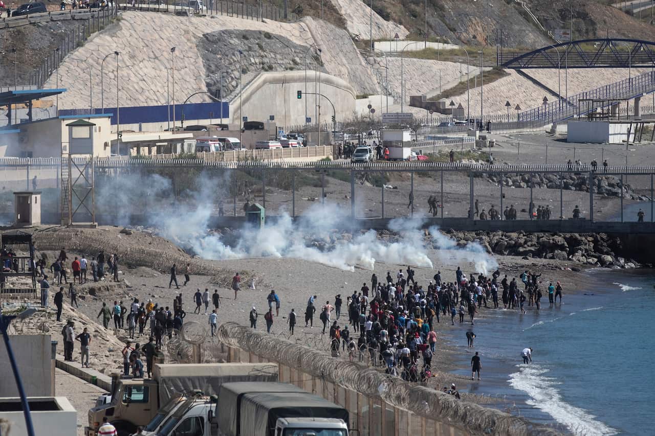 Spanish security forces throw tear gas at Moroccan and sub-saharan migrants attempting to cross the fence of the Spanish enclave of Ceuta.