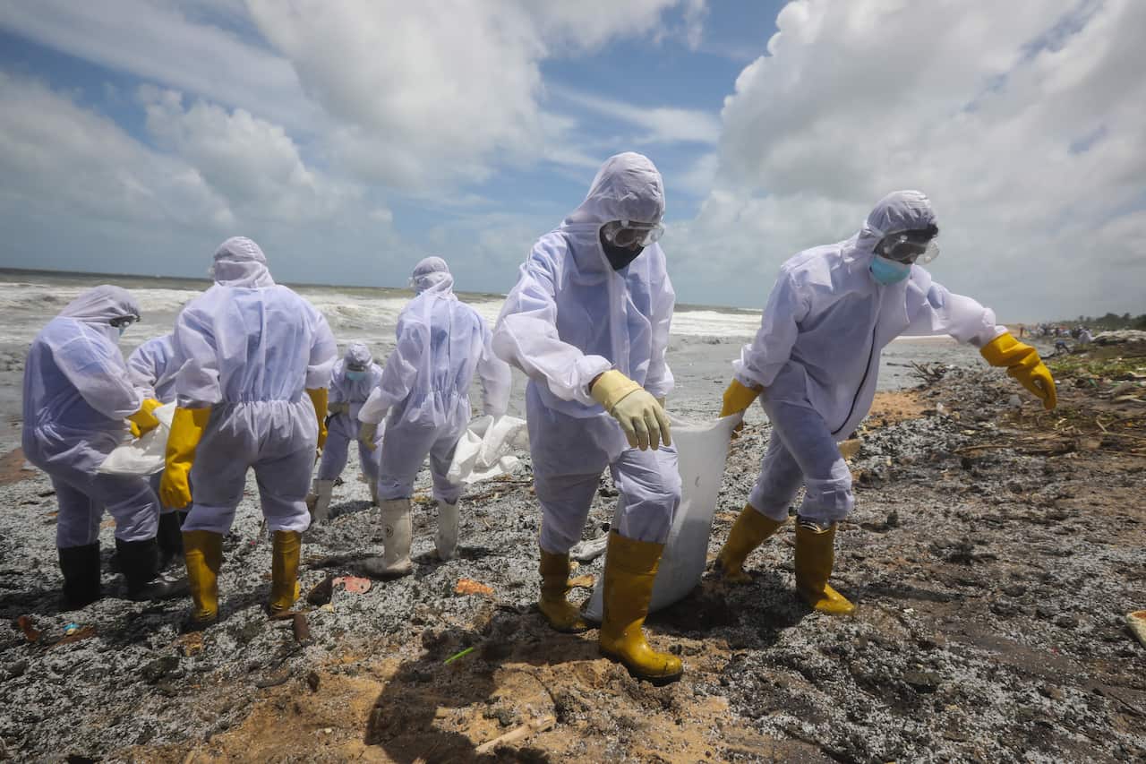 Sri Lanka Navy personnel clear the beach from debris from damaged containers on the burning cargo vessel MV X-Press Pearl, 27 May 2021.