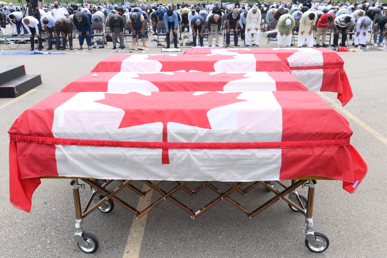 Mourners pray as caskets draped in Canadian flags are lined up at a funeral for the four Muslim family members killed in the attack