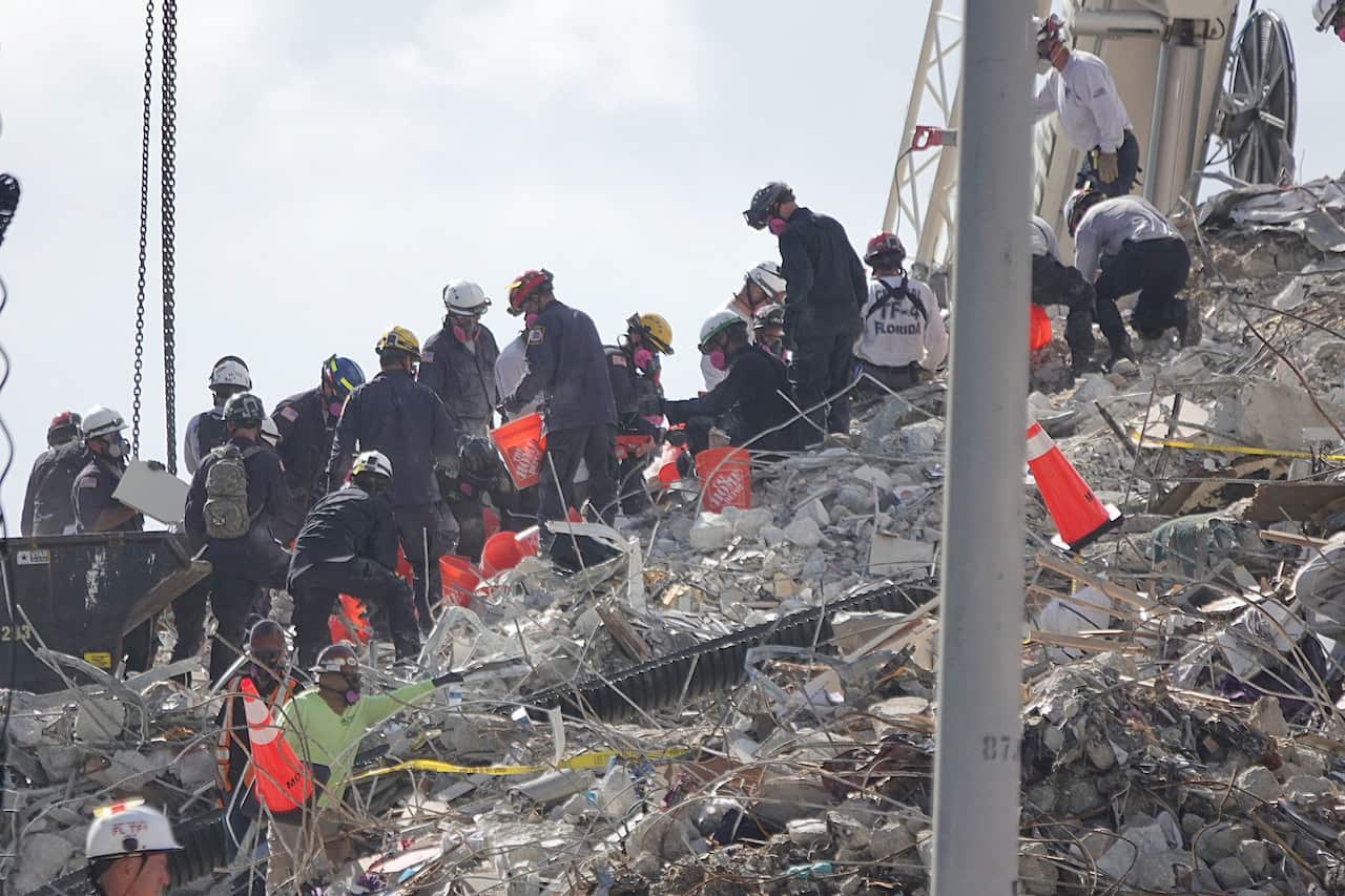 Rescue workers dig by hand using buckets at the site of the condo collapse in Surfside. 