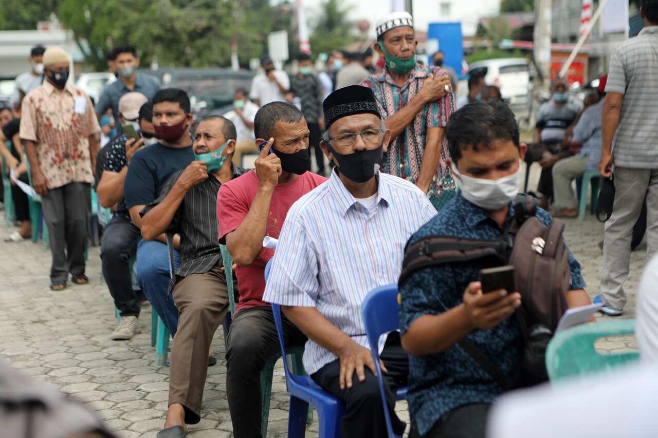 People queue to receives a dose of Sinovac vaccine during a mass vaccination for locals in Banda Aceh, Indonesia.