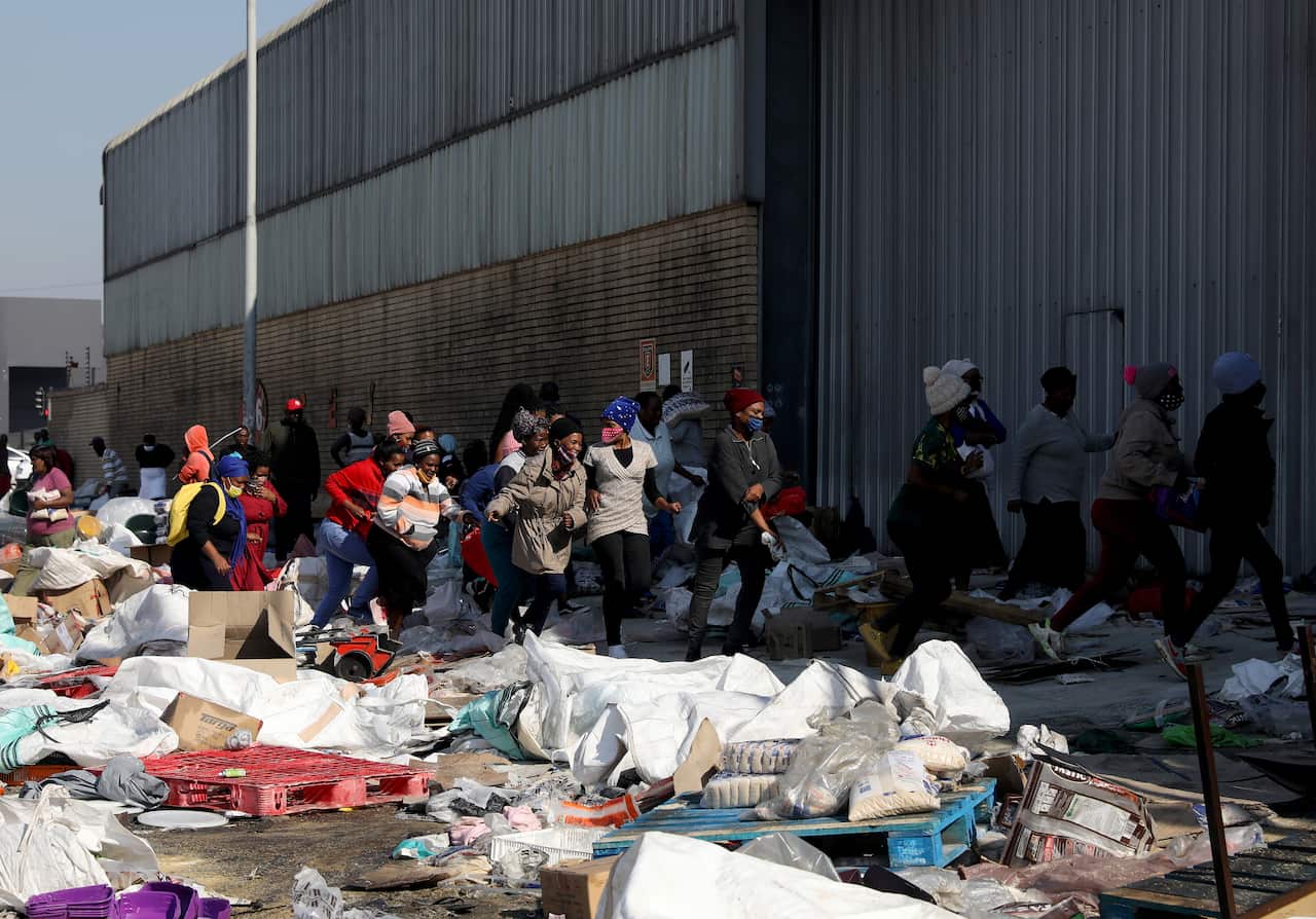 Women rush into the sugar warehouse in Mobeni as looting continues, in Durban, South Africa.