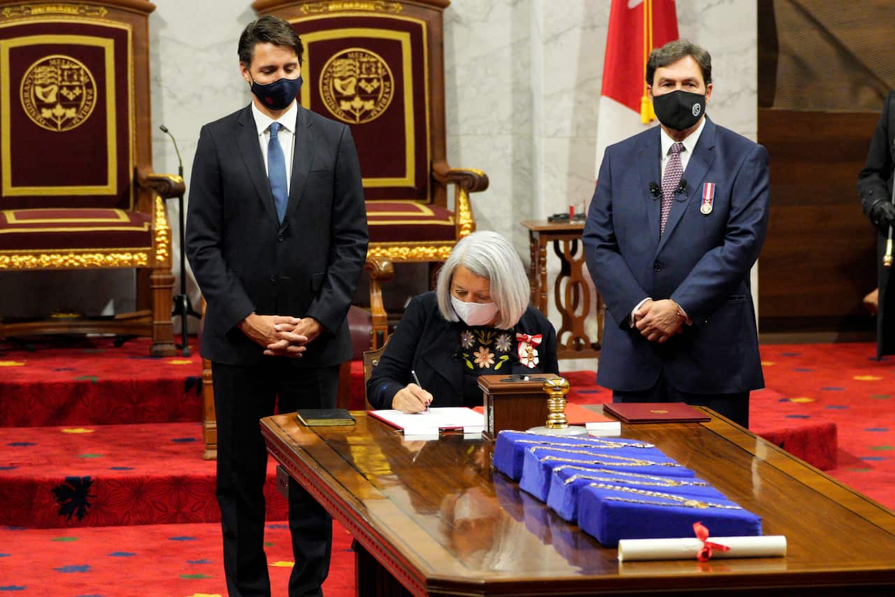 Mary Simon signs documents as Prime Minister Justin Trudeau looks on after she took the oath to become the 30th governor-general of Canada