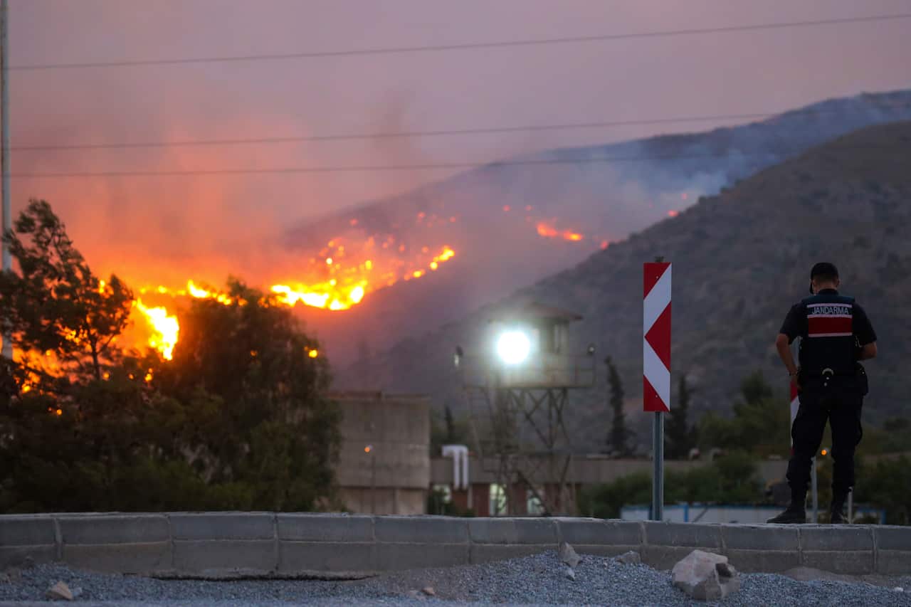 A paramilitary police officer stands by as a fire approaches in Milas, Mugla, Turkey.