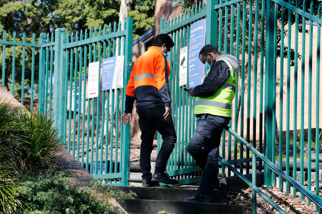 Security guards outside Morisset High School as it awaits deep cleaning after a student tested positive to COVID-19.
