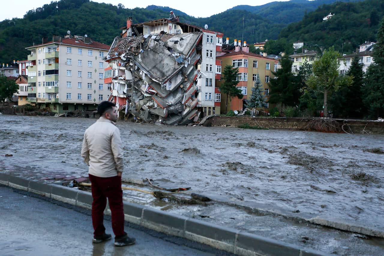 A man looks on as flood waters sweep by in Bozkurt town of Kastamonu province of Turkey, Thursday, Aug. 12, 2021. 