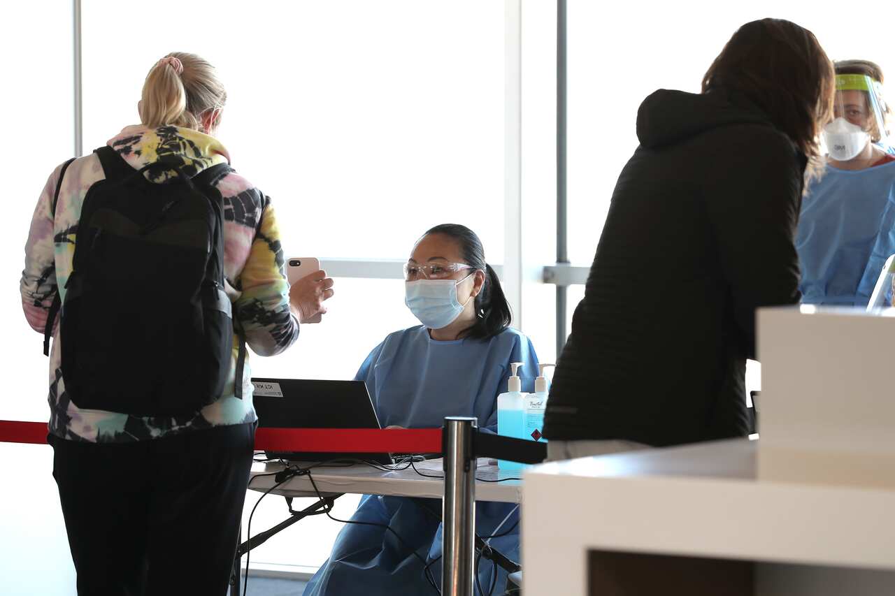 Health Care workers are seen checking passengers arriving from Sydney at Perth Airport