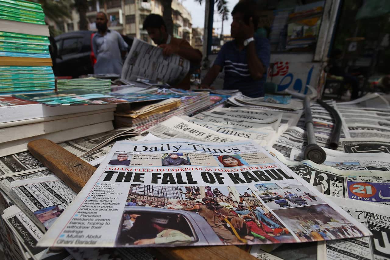 People read newspapers about the Taliban taking over Kabul at a stall in Karachi, Pakistan, 16 August 2021. 