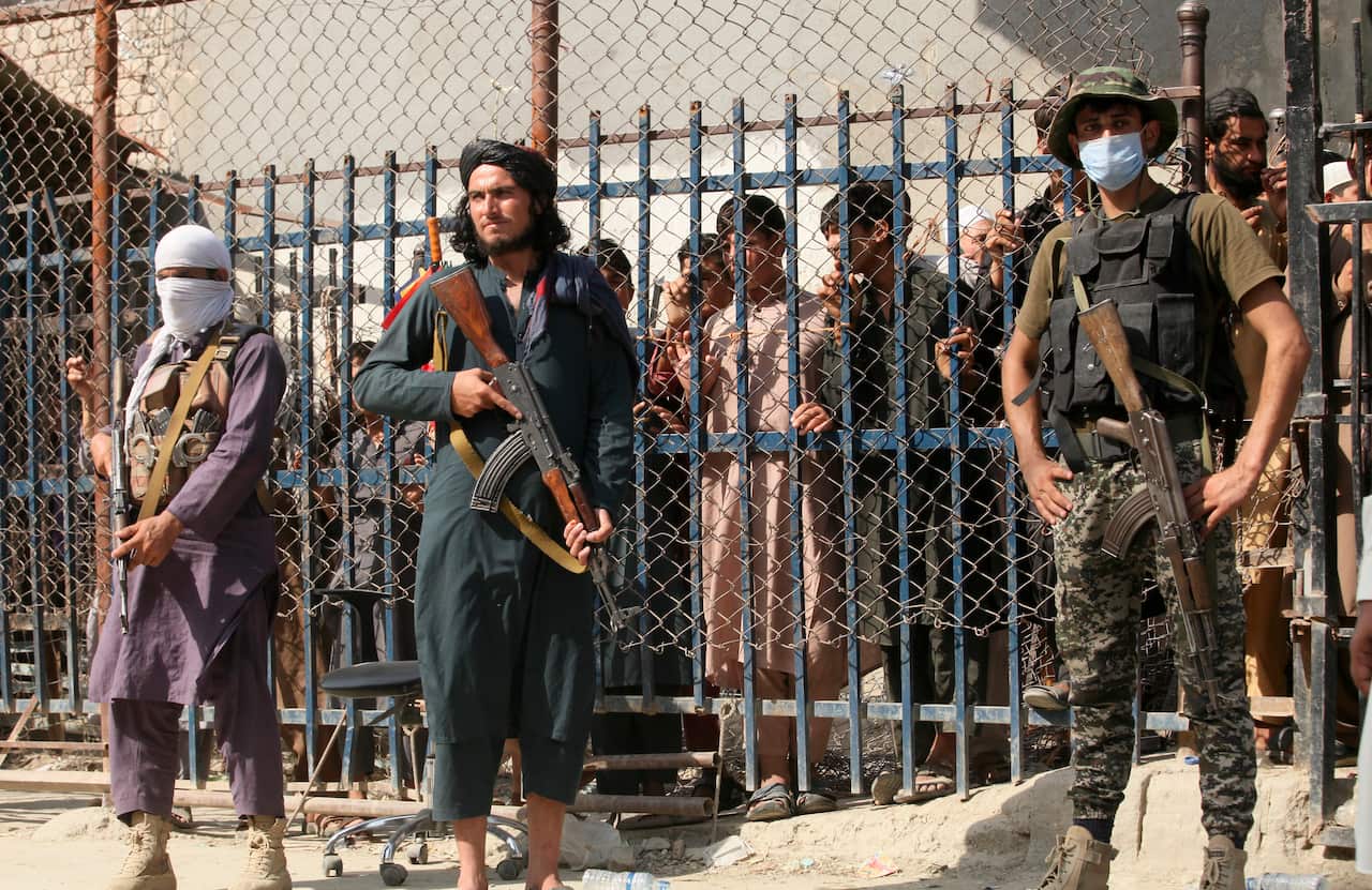 A Pakistani paramilitary soldier, right, and Taliban fighters stand guard at a border crossing point between Pakistan and Afghanistan, in Torkham.