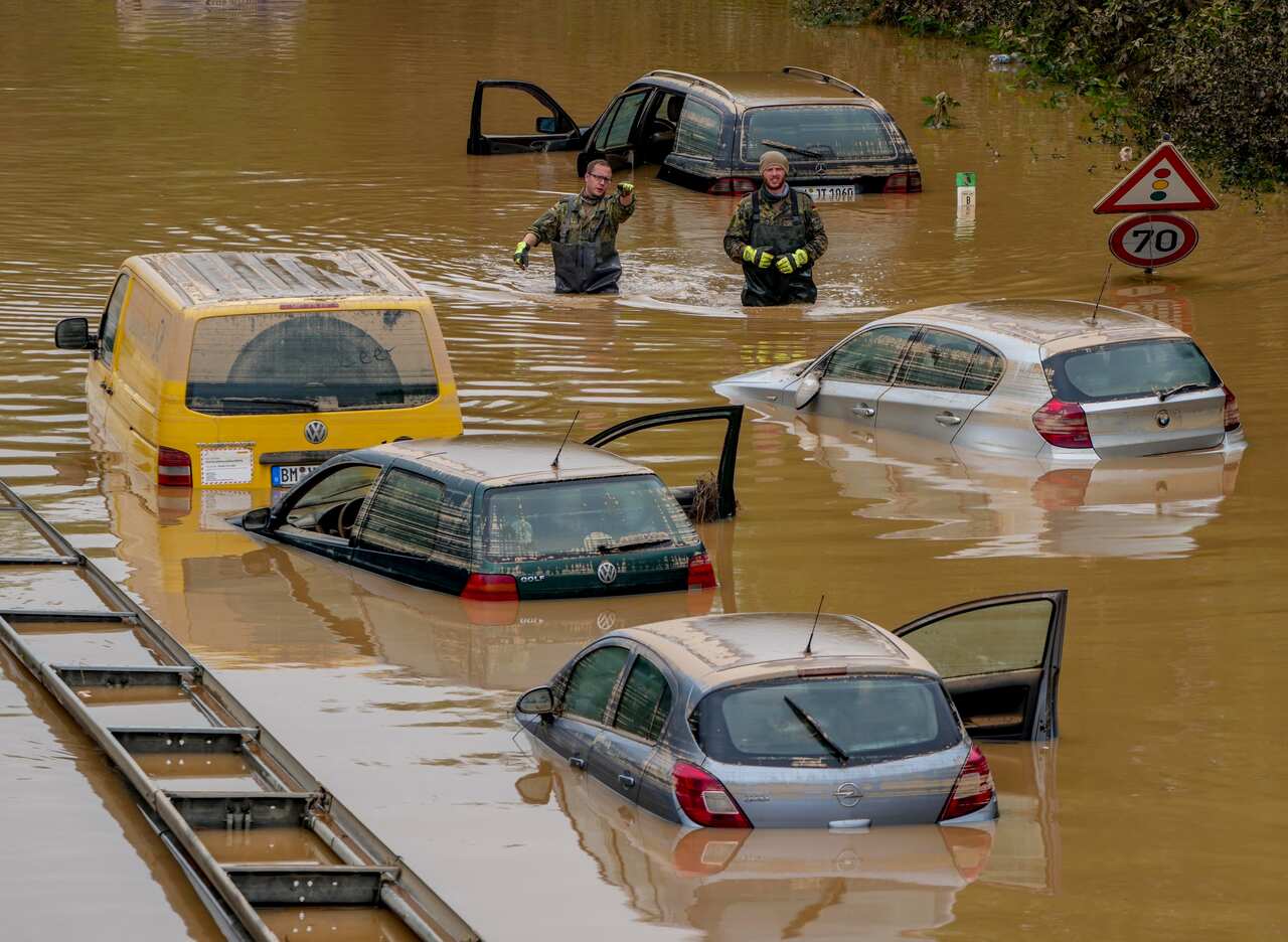 People check for victims in flooded cars on a road in Erftstadt, Germany, Saturday, July 17, 2021.