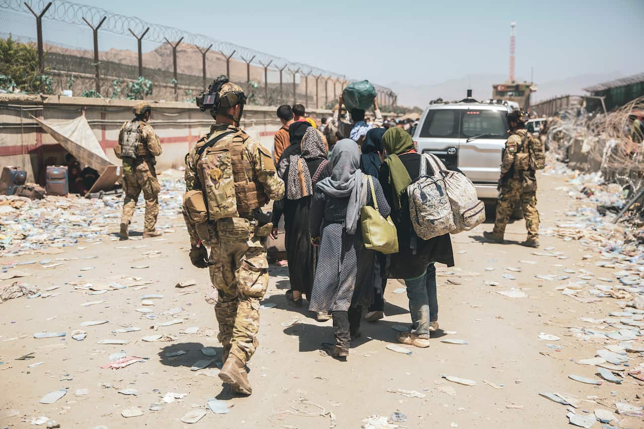 Italian coalition forces assist and escort evacuees for onward processing during an evacuation at Hamid Karzai International Airport in Kabul, Afghanistan, Tuesday, Aug. 24, 2021.