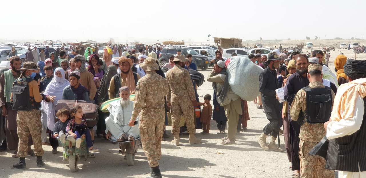 Pakistani soldiers check documents of people before crossing into Afghanistan at Chaman border point point, in Pakistan, 27 August 2021. 