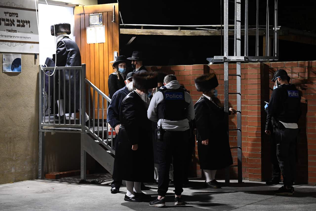 Victoria Police speak with people as they exit from a building near a Ripponlea synagogue in Melbourne, Tuesday, September 7, 2021.