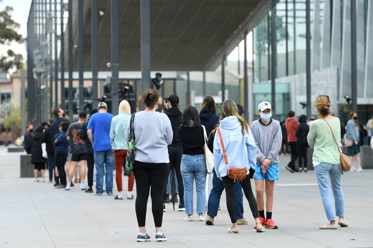 People are seen waiting in line at the Melbourne Museum for a COVID-19 vaccine.