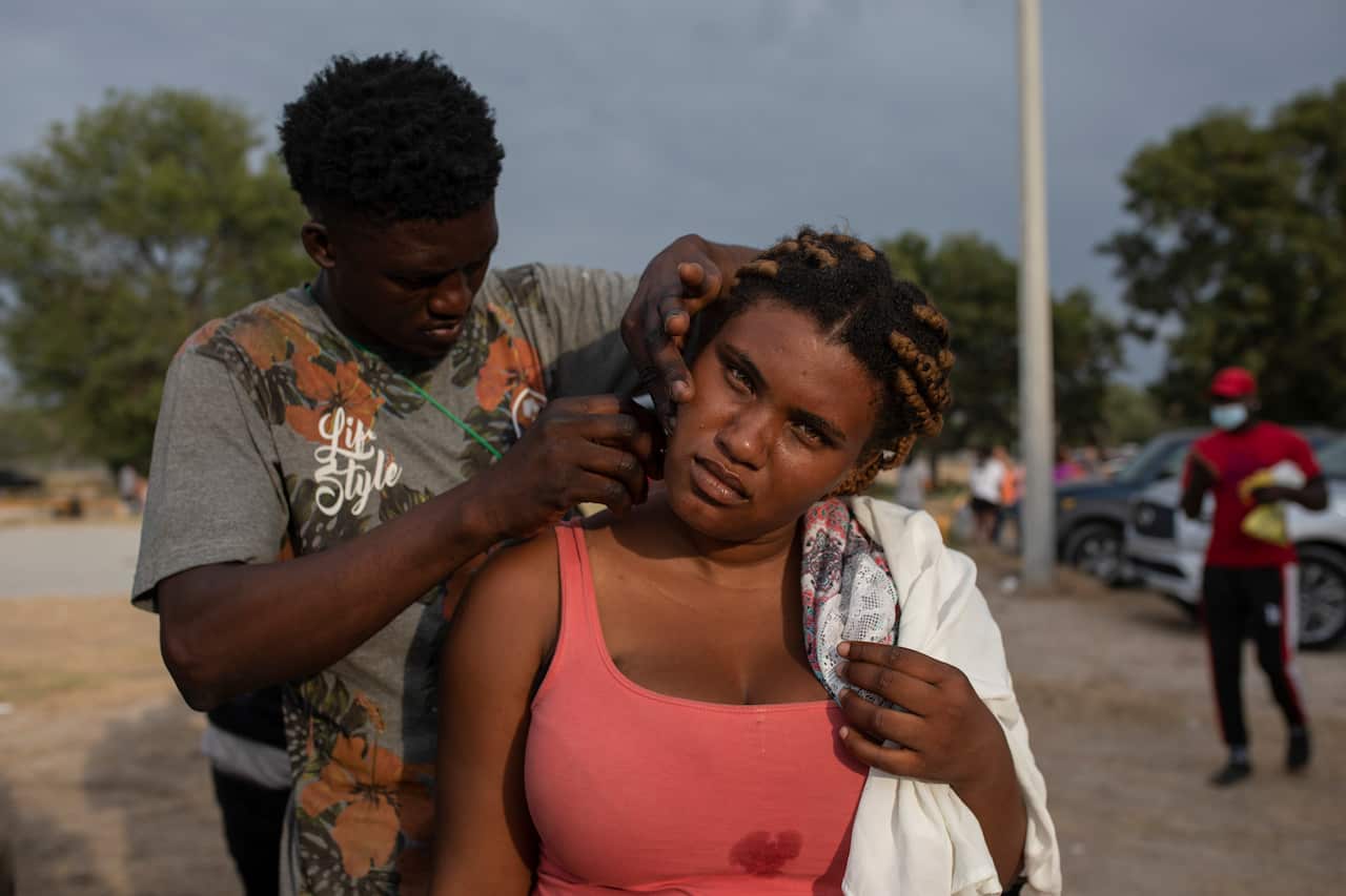 A migrant has her hair cut at an improvised refugee campt in Ciudad Acua, Mexico, Tuesday, Sept. 21, 2021
