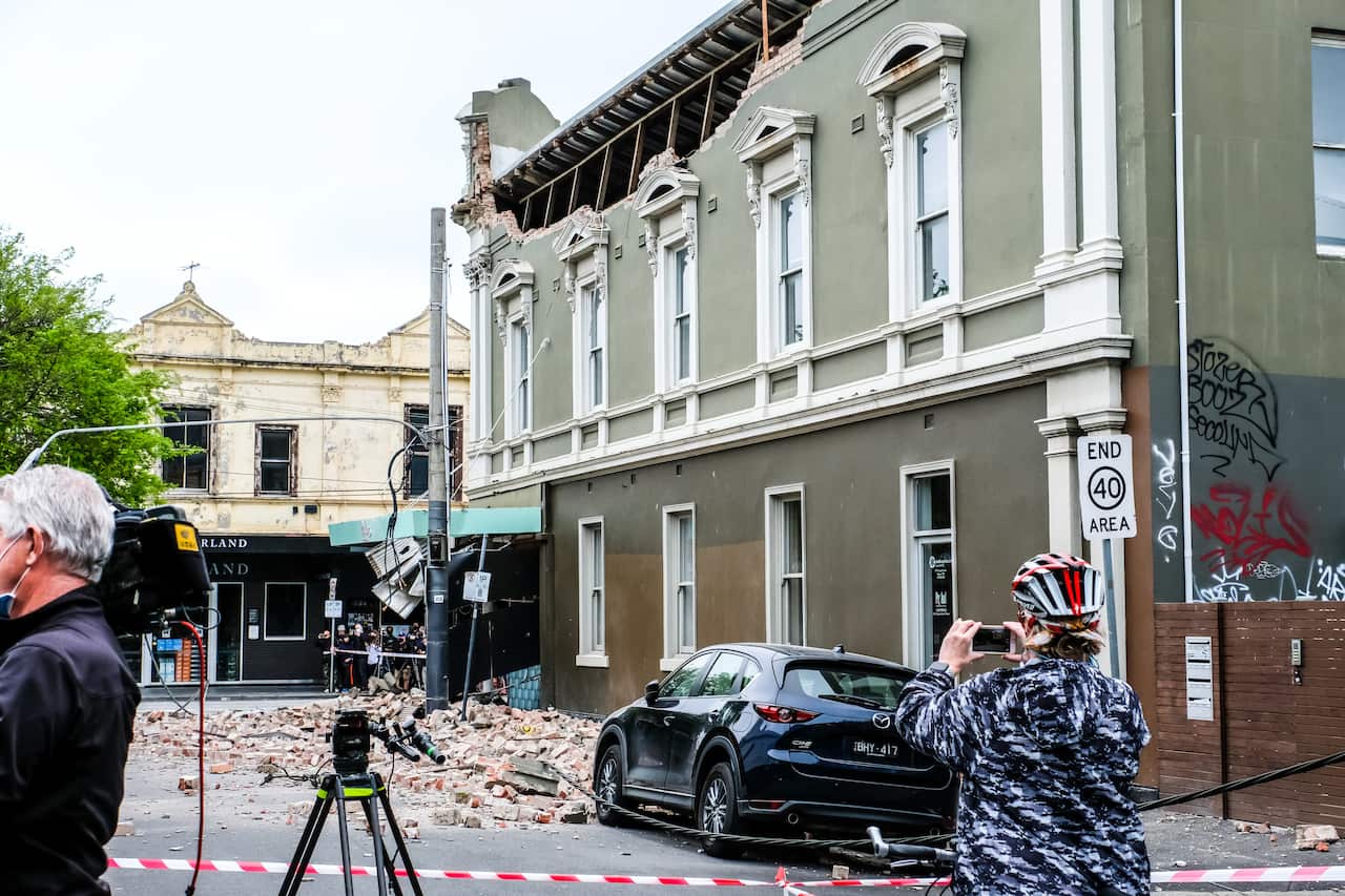 A woman taking photos of the damage caused by an earthquake in Melbourne during the aftermath.
