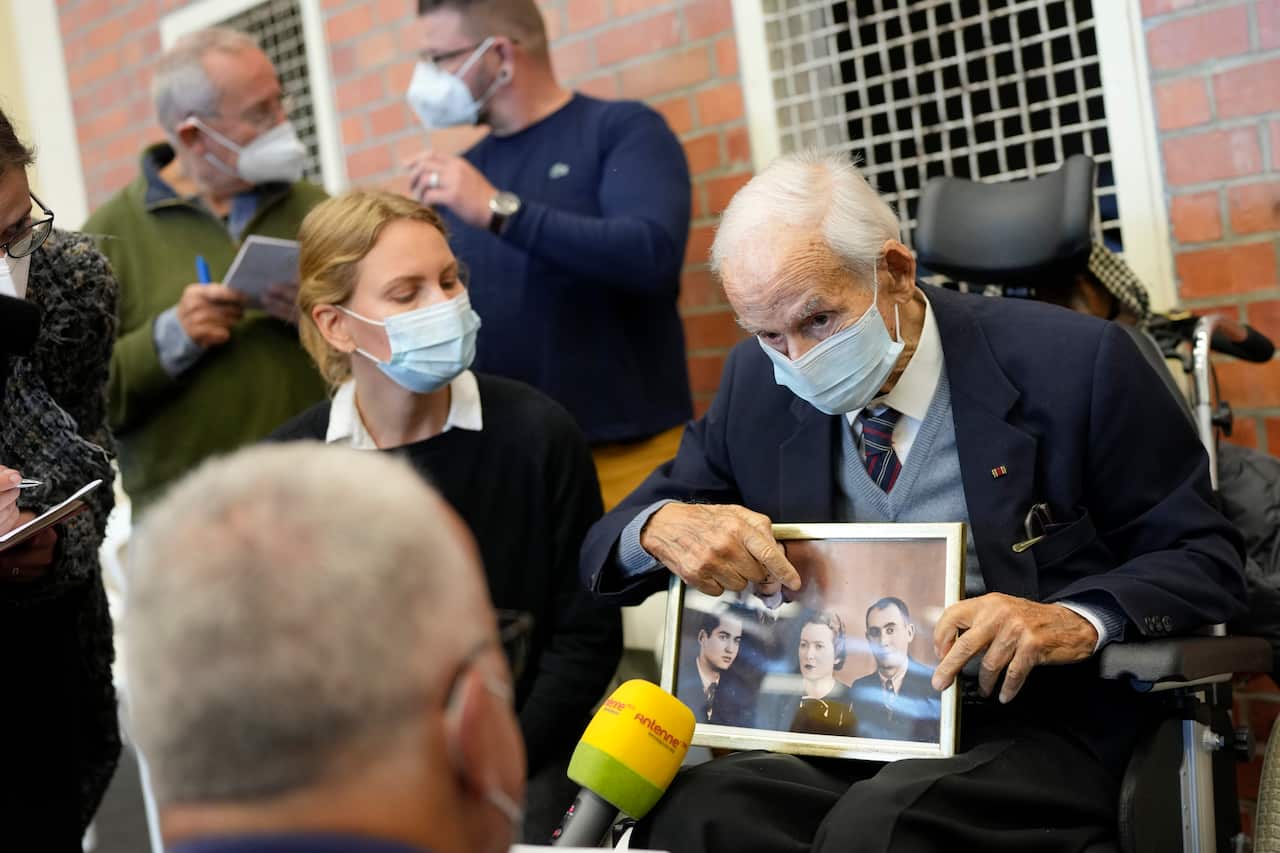 Leon Schwarzbaum, a 100-year-old Holocaust survivor, shows a family picture as he talks to media prior the trial against a former concentration camp guard.