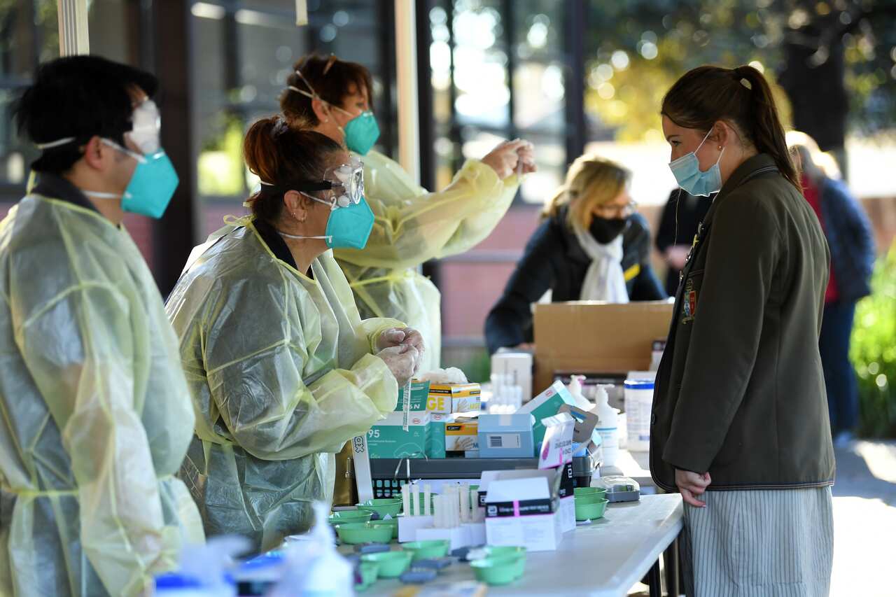 Firbank Grammar year 11 student Holly Fletcher (right) receives a COVID-19 Rapid Antigen test administer by a TLC Healthcare worker.