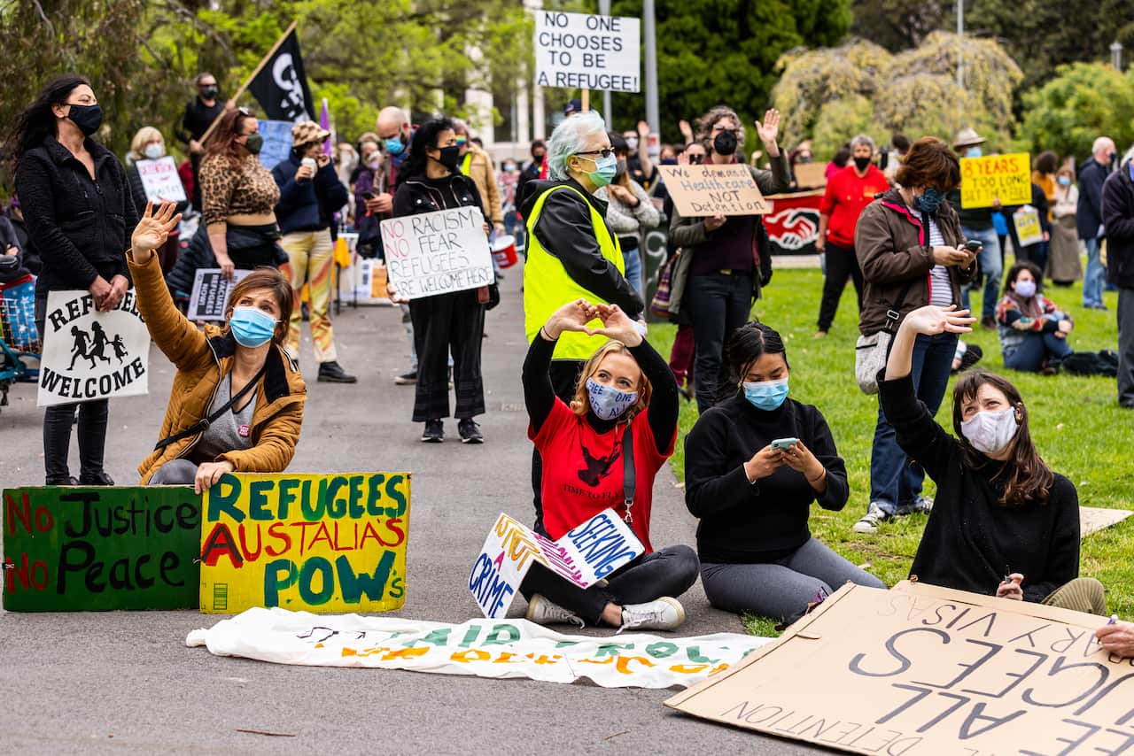 Refugee advocates wave to people inside the Park Hotel in Carlton whilst they participate in a 'Healthcare not detention' rally at Lincoln Square in Melbourne, Saturday, October 23, 2021. (AAP Image/Daniel Pockett) NO ARCHIVING