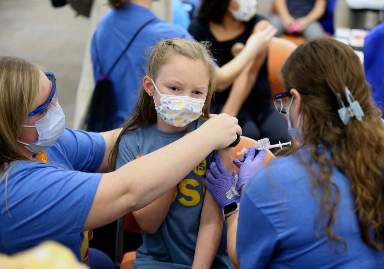 A child receives a Pfizer COVID-19 vaccine from a registered nurse. 