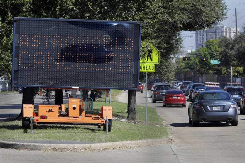 Traffic on Houston's Main Street passes by a sign announcing the cancellation of Astroworld