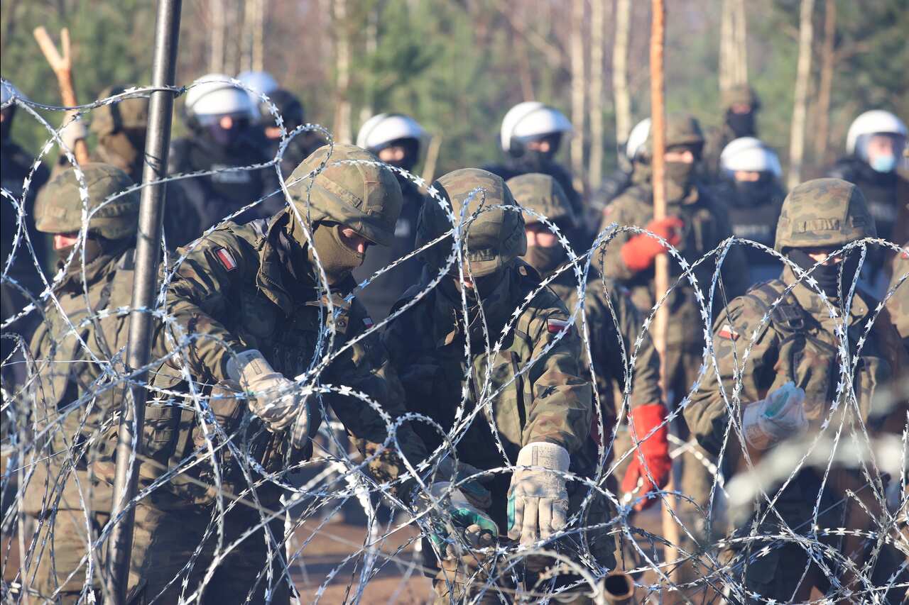 A handout picture shows Polish servicemen reinforcing the border line with barbed wire