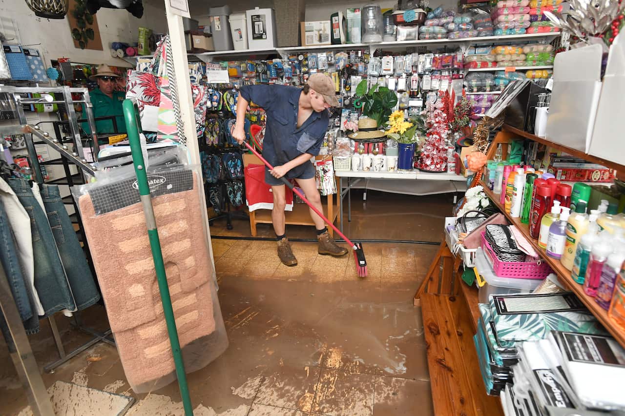 A man is seen cleaning flood waters from a gift shop business in the town of Inglewood, Queensland.