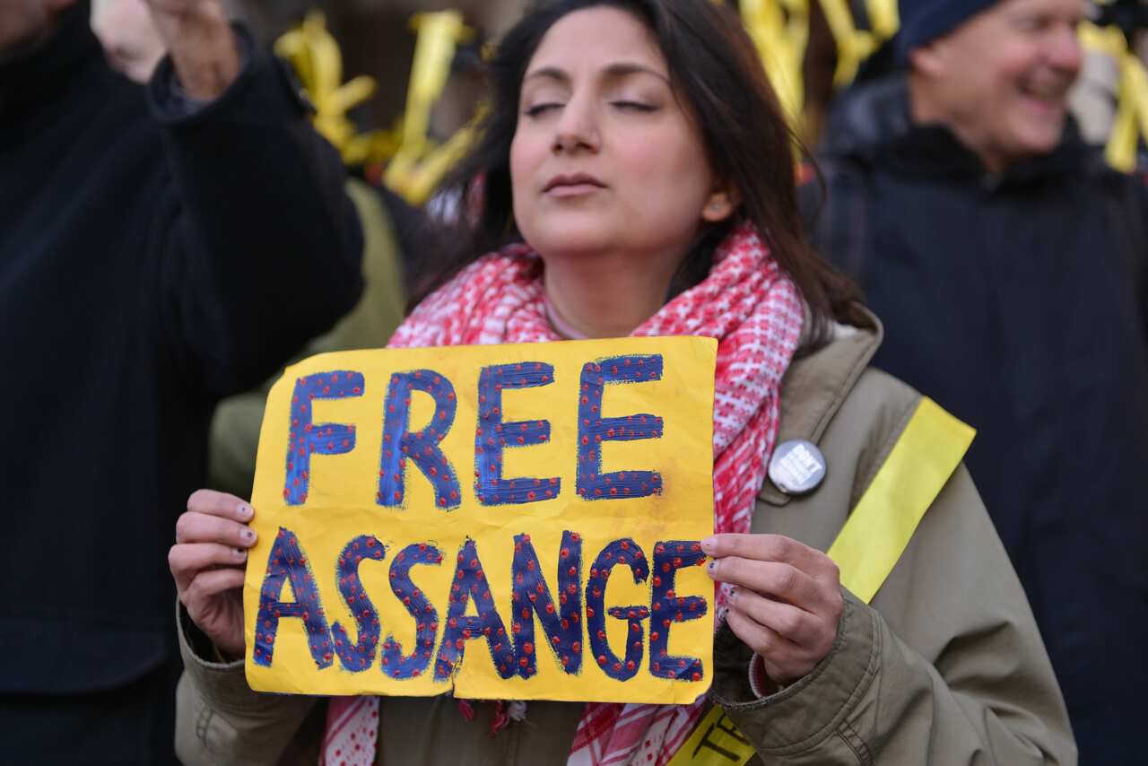 A protester seen with a placard in support of Julian Assange