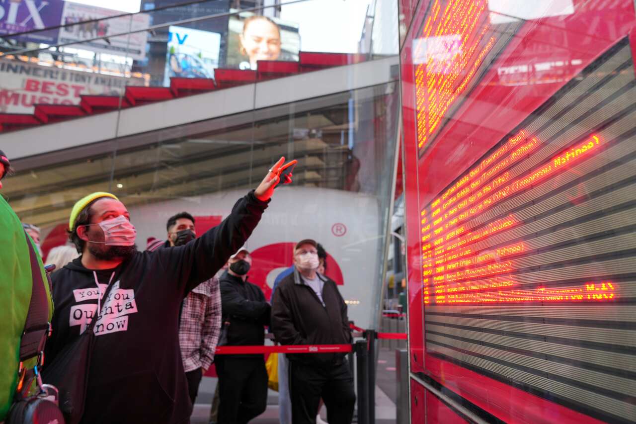 A man points at a chart with Broadway shows in the theatre district of New York City