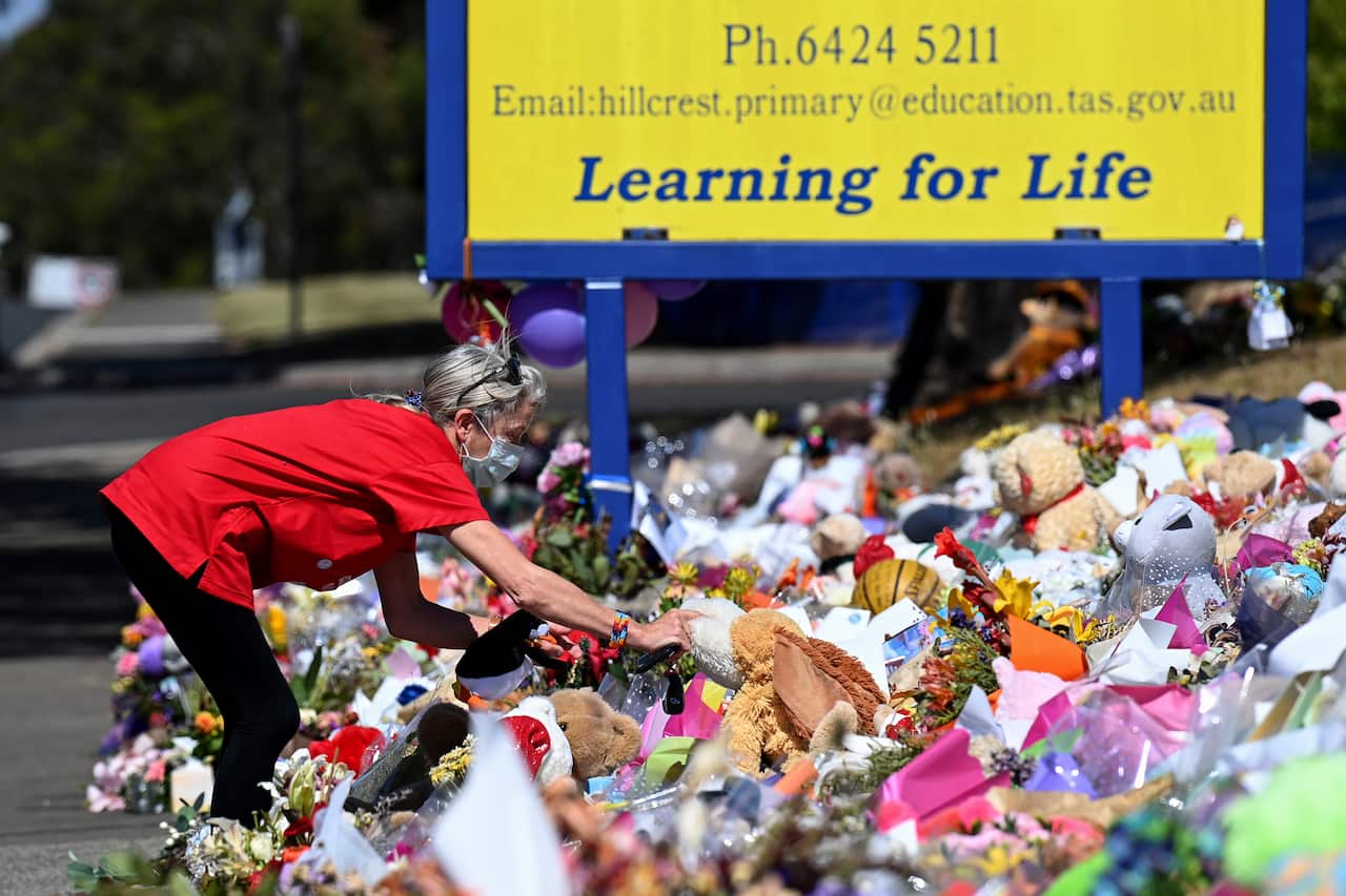 A woman leaving flowers outside the school