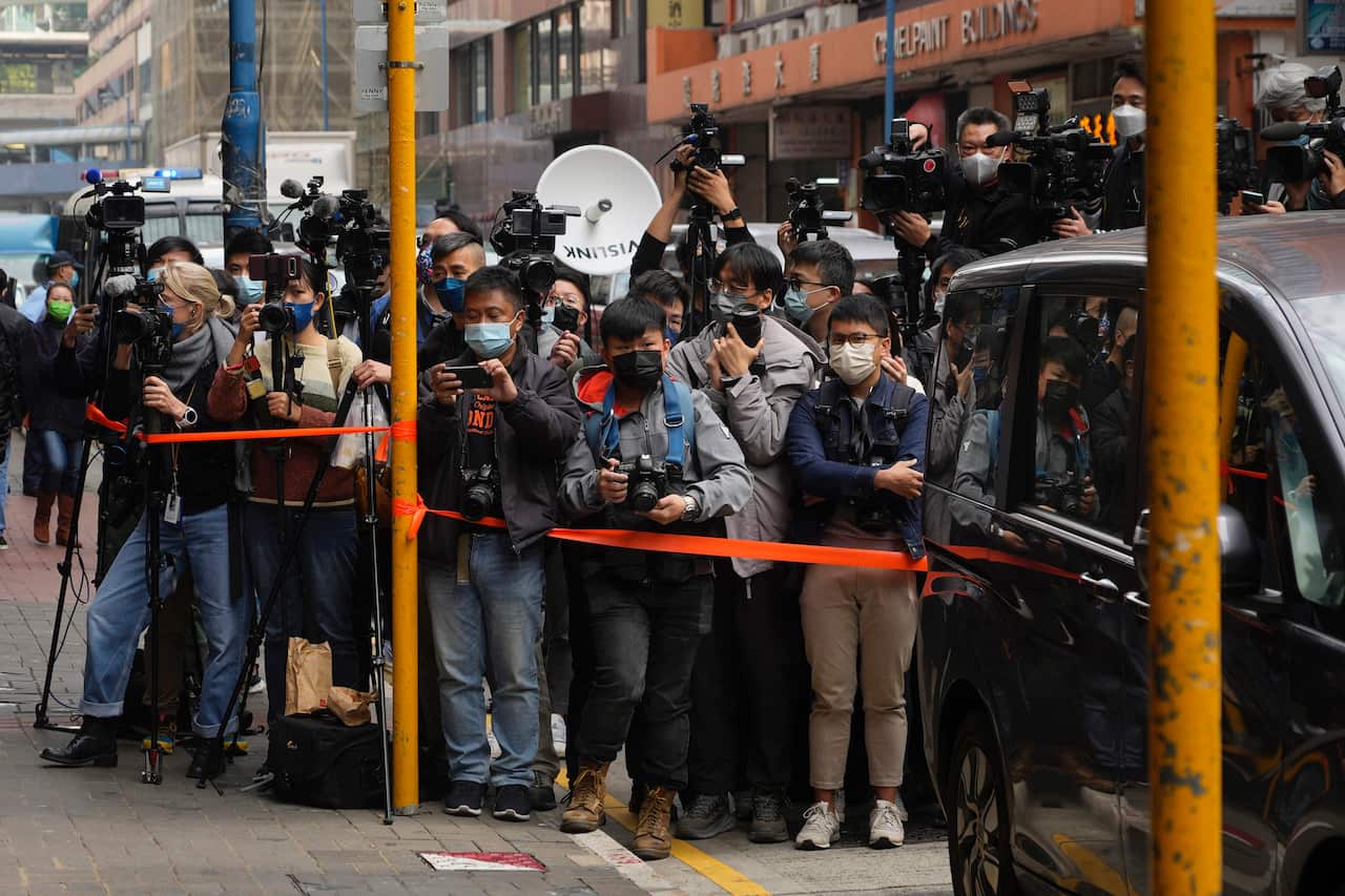 Journalists wait outside the building of the Stand News office