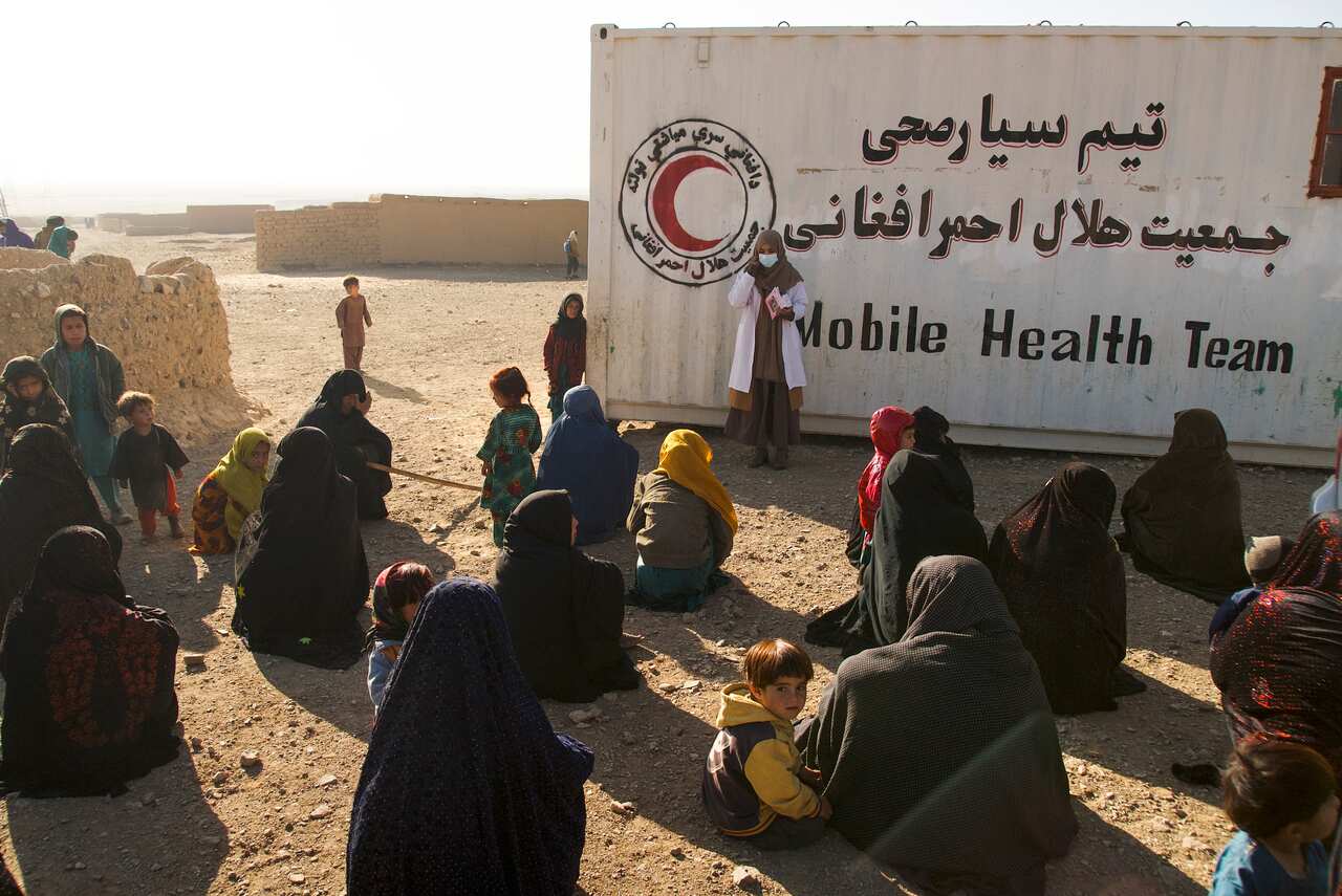 People gather near a makeshift clinic organised by IFRC at an IDP settlement near Herat