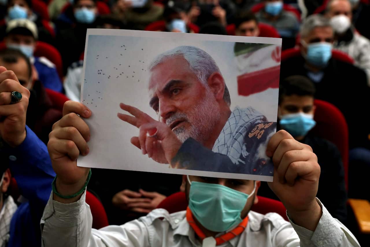 A man holds up a picture of General Qassem Soleimani during a ceremony to mark the second anniversary of his assassination.